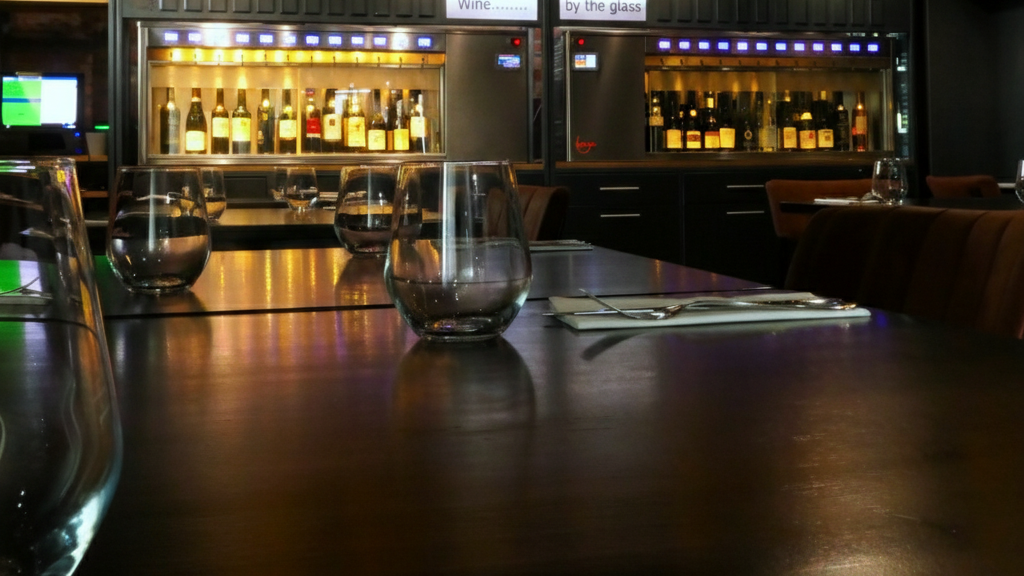 Bar interior with wine glasses and bottles, dimly lit ambiance