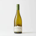 A bottle of Cloudy Bay White Sauvignon Blanc wine stands upright against a rustic stone wall background.